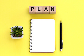 Notepad and pen on the background. Wooden cubes with word plan.