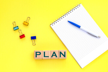 Notepad and pen on the background. Wooden cubes with word plan.
