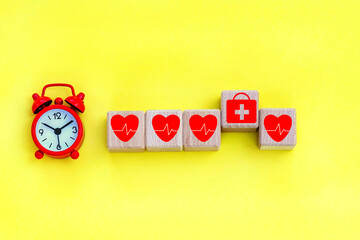 alarm clock.wood cubes with  healthcare medical icons on the background.