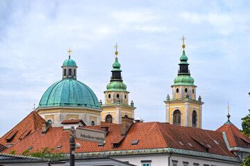 Fototapeta na wymiar Church tower and dome of cathedral at the old town of City of Ljubljana on a cloudy summer day. Photo taken August 9th, 2023, Ljubljana, Slovenia.