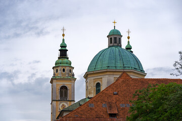Fototapeta premium Church tower and dome of cathedral at the old town of City of Ljubljana on a cloudy summer day. Photo taken August 9th, 2023, Ljubljana, Slovenia.