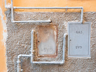 Old domestic protective metal box methane gas against a damaged varnished plaster wall with metal...