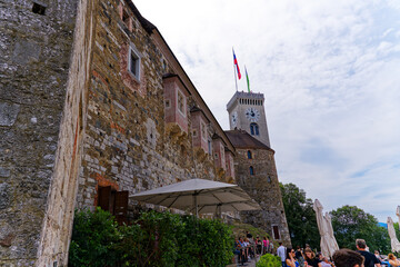 Looking up stone wall and tower with loophole of Castle of Ljubljana on a cloudy summer day. Photo...