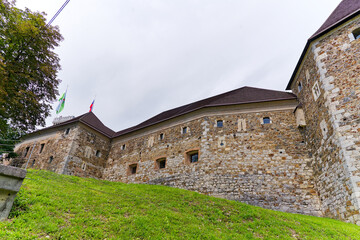 Looking up stone wall and tower with loophole of Castle of Ljubljana on a cloudy summer day. Photo...