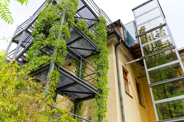 Fototapeta na wymiar Sightseeing at City of Ljubljana with close-up of metal balconies of yellow building covered with plants on a cloudy summer day. Photo taken August 9th, 2023, Ljubljana, Slovenia.