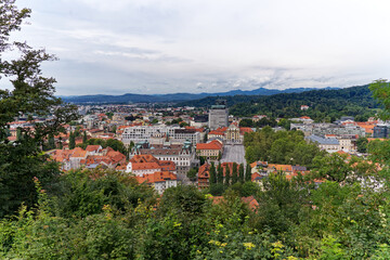 Aerial view of City of Ljubljana seen from Sance castle hill with mountain panorama in the background on a cloudy summer day. Photo taken August 9th, 2023, Ljubljana, Slovenia.