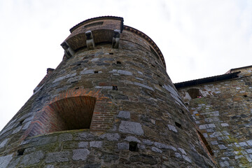Looking up stone wall and tower with loophole of Castle of Ljubljana on a cloudy summer day. Photo...