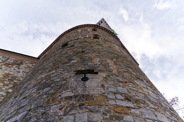 Looking up stone wall and tower with loophole of Castle of Ljubljana on a cloudy summer day. Photo...