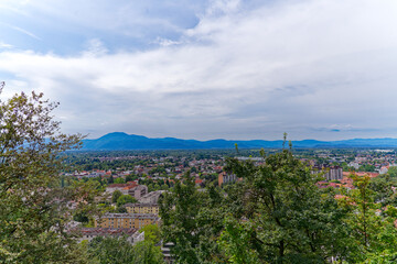 Obraz premium Aerial view of City of Ljubljana seen from Sance castle hill with mountain panorama in the background on a cloudy summer day. Photo taken August 9th, 2023, Ljubljana, Slovenia.