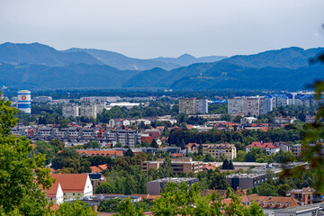 Fototapeta na wymiar Aerial view of City of Ljubljana seen from Sance castle hill with mountain panorama in the background on a cloudy summer day. Photo taken August 9th, 2023, Ljubljana, Slovenia.