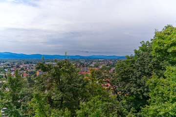 Fototapeta na wymiar Aerial view of City of Ljubljana seen from Sance castle hill with mountain panorama in the background on a cloudy summer day. Photo taken August 9th, 2023, Ljubljana, Slovenia.