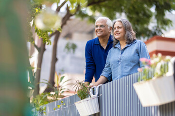Smiling Indian senior couple with hands clasped looking away
