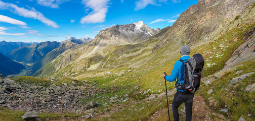 Hiker man on alpine meadow with panoramic view of majestic mount Gamskarlspitz in High Tauern...