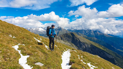 Hiker man on alpine meadow with panoramic view of majestic mount Hochalmspitze in High Tauern...