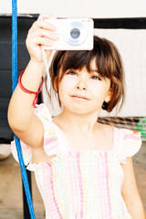 6-year-old Spanish girl taking a photo with a small digital camera. Vertical.