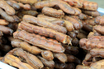 Tropical tamarind fruit without a shell, with visible seeds and inner pulp, in a galvanized tray on a wooden. Concept of food preservation in Thai style. Peeled tamarind is a ready-to-eat concept.