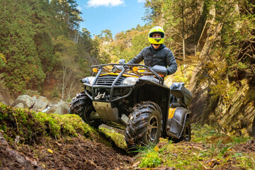 Man on quad bike. Racer rides off-road. Quad bike for racing in mountainous areas. ATV driver looks...