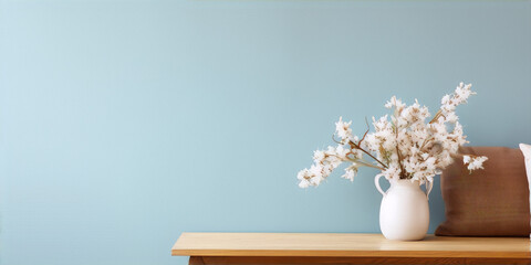 Dried flowers in white vase on wooden table against blue wall