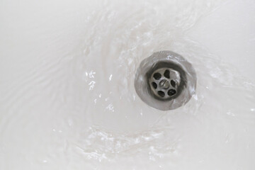 Swirl of water flows down the drain in the bathroom.