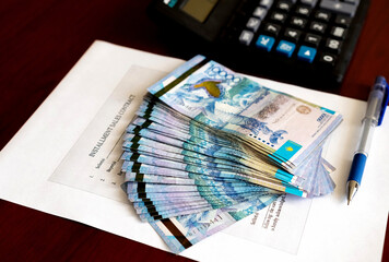 Tenge. Paper Kazakh money and calculator on the table close-up.