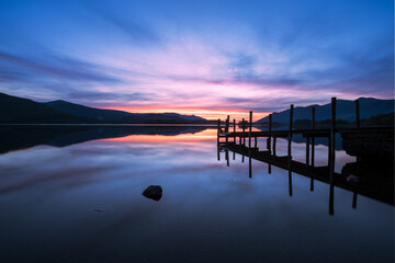 Fototapeta na wymiar Vivid sunset colours with reflections in Derwentwater at Ashness Jetty, Lake District, UK.