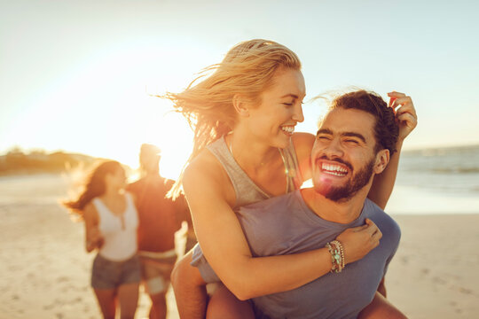 Happy couple laughing and having fun at the beach during sunset