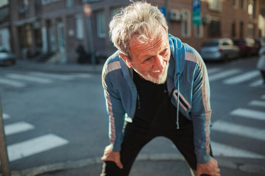 Exhausted elderly man catching breath after running in the city