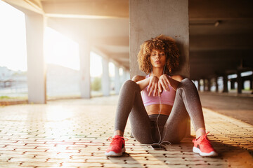Young woman taking a break from jogging and exercising in a parking lot