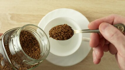 Hand adds instant coffee to a white mug, close-up - Powered by Adobe
