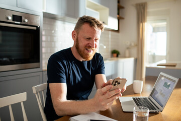Young man using smartphone at home - obrazy, fototapety, plakaty