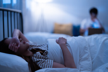 Asian insomnia woman lying awake in bed with a blurred background and frustration of sleepless and...