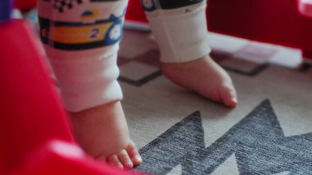 Baby boy's feet standing on the floor in a walker
