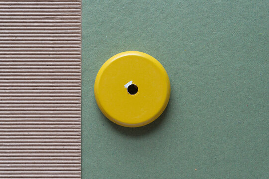 yellow object with hole on green and brown paper with texture