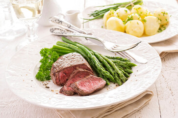 Traditional roasted angus beef steak with green asparagus and boild potatoes served as close-up on a classic plate