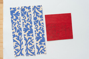 red square with ghosting pattern and a set of paper stripes with decorative blue and tan pattern