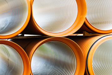 Large diameter pipes lie on the ground against the backdrop of a multi-storey residential building....