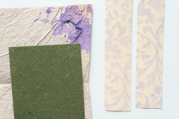 green paper tile on textured stained paper and the reverse of paper ribbons with decorative pattern