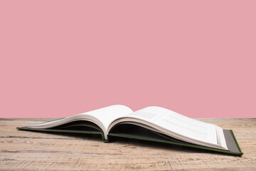 open book. Composition with hardback books, fanned pages on wooden deck table and pink background. Books stacking. Back to school. Copy Space. Education background.