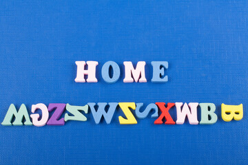 HOME word on blue background composed from colorful abc alphabet block wooden letters, copy space for ad text. Learning english concept.