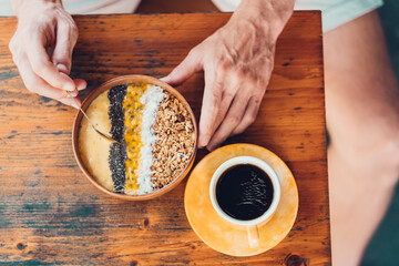 Man having breakfast with americano coffee and smoothie bowl. Top view.
