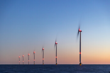 Off shore wind turbines or wind mills at sea at blue dusk long exposure