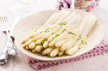 Traditional German white  asparagus with souce hollandaise served as close-up on a design plate