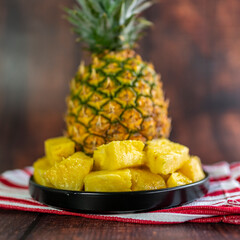 Pineapple slices on a black plate on a wooden table. Healthy fruit.