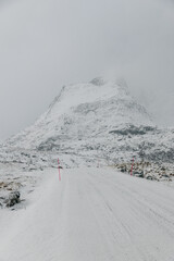 Icy road on Lofoten Islands with snow covered mountains and cloady skies