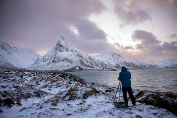 Photographer in snowy landscape with mountains and pink sky - Powered by Adobe