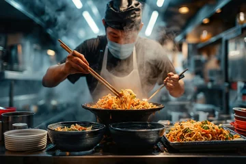 Foto op Canvas A man is seen in a kitchen using chopsticks to prepare food, possibly Japanese ramen. He is focused on the task at hand. © Joaquin Corbalan