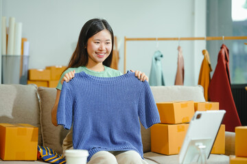 young Asian entrepreneur, the owner of a small clothing store, organizes online live streams...