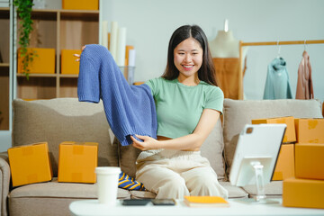 young Asian entrepreneur, the owner of a small clothing store, organizes online live streams...