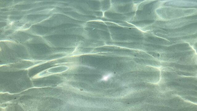 Light blue, ripped, clear and transparent sea water with sun glares, water movements, moving water