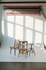 three chairs and a stool are sitting in front of a white wall